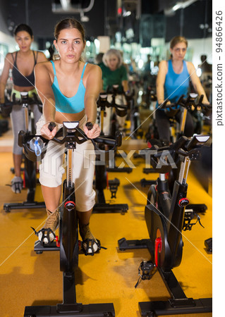 Woman taking indoor cycling class at gym Woman taking indoor cycling class at gym 94866426