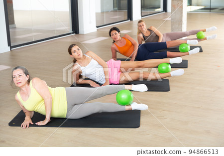 Women exercising with ball during group pilates class 94866513