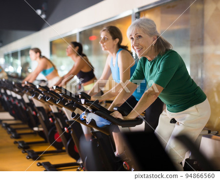 Mature woman taking cycling class at gym 94866560