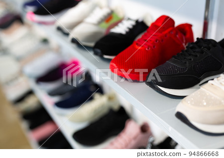 Different colorful sport shoes are on shelves 94866668