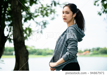 Asian woman wearing jacket is engaged in fitness in public park 94867971