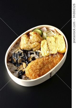 A bird's-eye view of a seaweed valve with a rolled egg and chicken cutlet on a black background 94868326