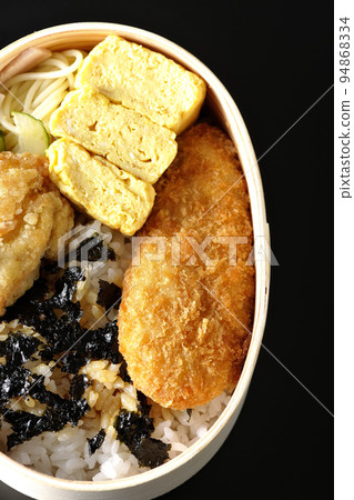 A bird's-eye view of a seaweed valve with a rolled egg and chicken cutlet on a black background A bird's-eye view of a seaweed valve with a rolled egg and chicken cutlet on a black background 94868334