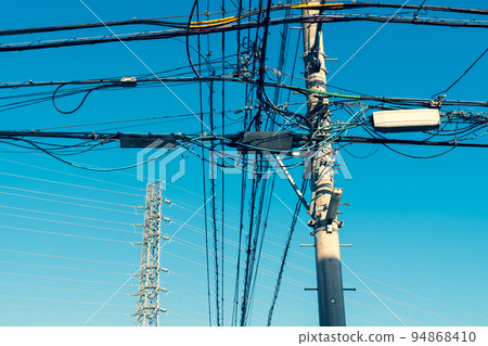 Power transmission tower that supports the intricate wires and high-voltage transmission lines in the residential area b-3 warm colors 94868410