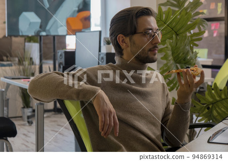3d game artist works at a computer in the office and eats a big pizza 3d game artist works at a computer in the office and eats a big pizza 94869314