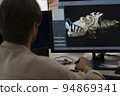 Caucasian designer draws by stylus on tablet 3D models for games. 94869341