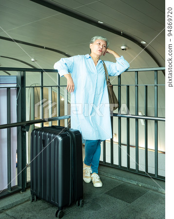 Portrait of senior adult elderly asian woman 60s smiling standing with suitcase luggage bag and holding passport with ticket for travel concept. Portrait of senior adult elderly asian woman 60s smiling standing with suitcase luggage bag and holding passport with ticket for travel concept. 94869720