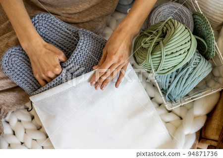 Woman designer hands packing handmade knitting ribbon yarn slippers into branding pack sending order 94871736
