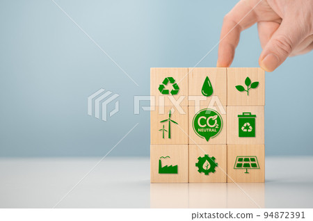 Climate neutral long term strategy. Hand put wooden cubes with green icon and green icon on blue background. Carbon neutral sustainable development concept. Green industry. 94872391