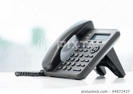 telephone devices at white office desk with light effect, communication technology concept. VOIP or IP phone. Modern Phone VoIP. Communication support, call center and customer service help desk 94872437