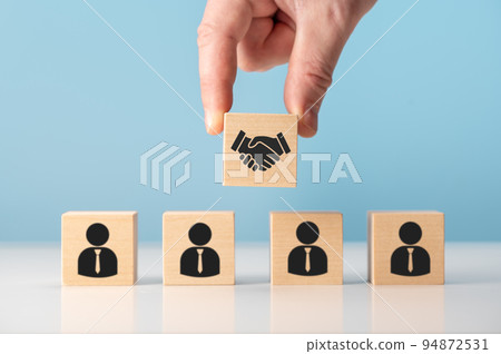 business contract. Hand putting hand shaking which print screen on wooden cube block in front of human icon for business deal and agreement concept. business contract. Hand putting hand shaking which print screen on wooden cube block in front of human icon for business deal and agreement concept. 94872531