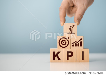KPI - Key Performance Indicator. Businessman holds cube with KPI icon, business goals, performance results and indicators. Target evaluation and analytical numbers for marketing KPI management 94872601