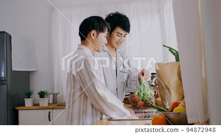 Asian people happy time smile, laugh in kitchen. Best friend LGBTQ lifestyle. Happy Asian gay couple homosexual cooking together in kitchen prepare fresh vegetable make organic salad healthy food. 94872948