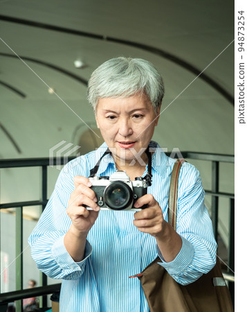 60 multi-year-old Asian women wield a single-eye view machine or a bottom single-phase machine, travel or sightseeing exploration concept. 94873254