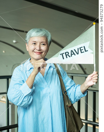 60歲亞洲老太婆畫像,微笑,駐紮手袋,提箱,手持旗桿,移動旅行樂隊的概念。 60歲亞洲老太婆畫像,微笑,駐紮手袋,提箱,手持旗桿,移動旅行樂隊的概念。 94873279