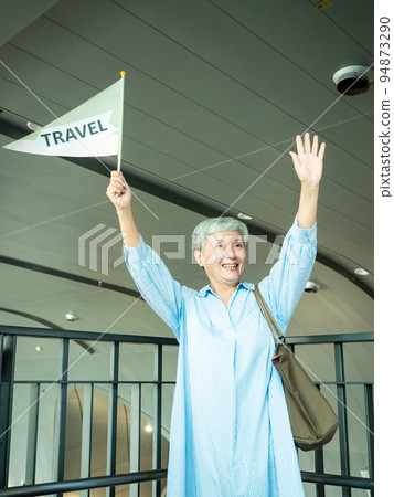 60歲亞洲老太婆畫像,微笑,駐紮手袋,提箱,手持旗桿,移動旅行樂隊的概念。 60歲亞洲老太婆畫像,微笑,駐紮手袋,提箱,手持旗桿,移動旅行樂隊的概念。 94873290