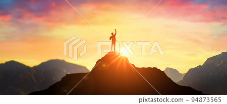 Man on mountain peak with open arms welcoming new day with sunrise. Success. successful man with hands up on peak of mountain at sunset. Successful person 94873565