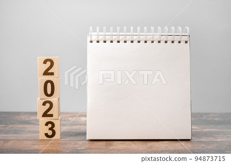 Mockup 2023 calendar. Text 2023 on wooden cubes. space for your text on notepad, mockup calendar. New Year. startup concept. Year 2023 and notepad 94873715