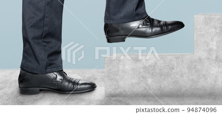 Side view of man climbing concrete stairs. Concept of success and achieving your goal. Man takes step in classic shoes. Low Section of Businessman Walking Up on Staircase Side view of man climbing concrete stairs. Concept of success and achieving your goal. Man takes step in classic shoes. Low Section of Businessman Walking Up on Staircase 94874096