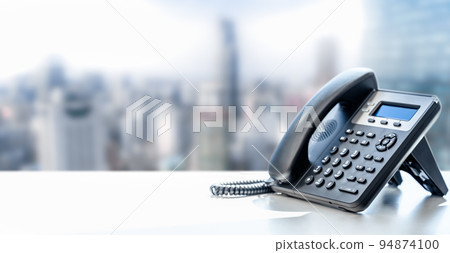 telephone with VOIP on white table on blurred city background. customer service support, call center concept. telephone devices at office desk. Modern Phone VoIP telephone with VOIP on white table on blurred city background. customer service support, call center concept. telephone devices at office desk. Modern Phone VoIP 94874100