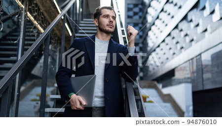 a male cybersecurity specialist in a business suit on the background of the stairs of an office 94876010