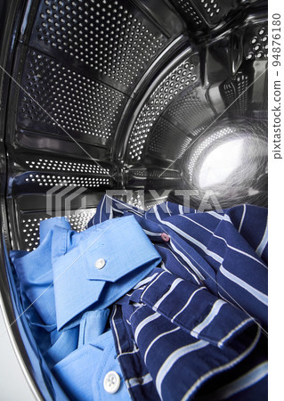 Close-up of an open door in washing machine with dirty shirts inside 94876180