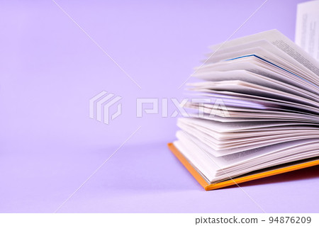 A part of an open book on purple background 94876209