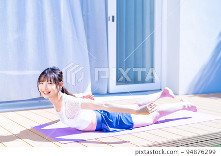 Young woman doing yoga on wooden deck 94876299