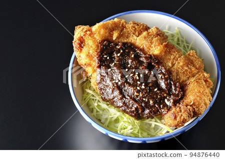 A bird's-eye view of a miso katsudon with plenty of cabbage on a black background 94876440