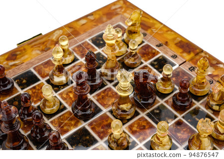 Natural amber different chess pieces figures standing on brown stone board. Close up game concept competition, Classic Gambit Tournament of confrontation. Natural amber different chess pieces figures standing on brown stone board. Close up game concept competition, Classic Gambit Tournament of confrontation. 94876547