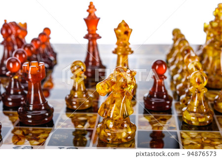 Natural amber different chess pieces figures standing on brown stone board. Close up game concept competition, Classic Gambit Tournament of confrontation. Natural amber different chess pieces figures standing on brown stone board. Close up game concept competition, Classic Gambit Tournament of confrontation. 94876573