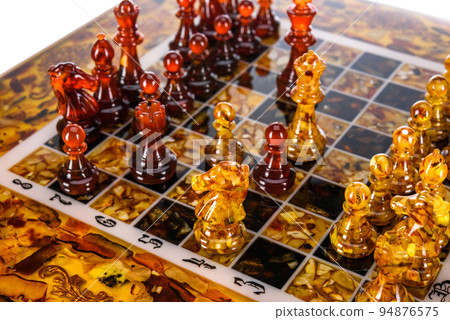 Natural amber different chess pieces figures standing on brown stone board. Close up game concept competition, Classic Gambit Tournament of confrontation. Natural amber different chess pieces figures standing on brown stone board. Close up game concept competition, Classic Gambit Tournament of confrontation. 94876575