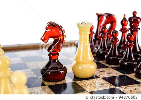 Natural amber different chess pieces figures standing on brown stone board. Close up game concept competition, Classic Gambit Tournament of confrontation. Natural amber different chess pieces figures standing on brown stone board. Close up game concept competition, Classic Gambit Tournament of confrontation. 94876602