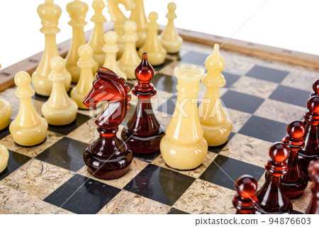 Natural amber different chess pieces figures standing on brown stone board. Close up game concept competition, Classic Gambit Tournament of confrontation. Natural amber different chess pieces figures standing on brown stone board. Close up game concept competition, Classic Gambit Tournament of confrontation. 94876603