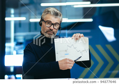 Video call, senior gray-haired businessman looking at camera and showing report financial graph, man not satisfied with financial report, online meeting with colleagues executives investors. 94877646