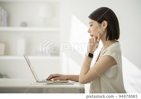 Profile of a young woman working on a laptop 94878065