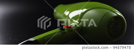 Green professional hairdryer device lay on black background, tool for beauty master 94879478