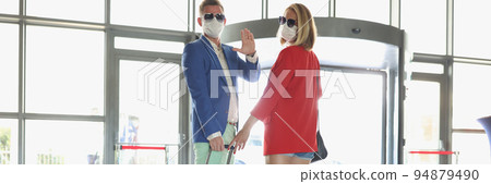 Couple dressed in luxury suits with suitcase wave goodbye before flying on vacation Couple dressed in luxury suits with suitcase wave goodbye before flying on vacation 94879490