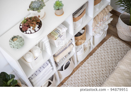 Neatly folded linen cupboard shelves storage at eco friendly straw basket placed closet organizer 94879951