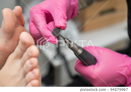 Woman on professional pedicure procedure by abrasive disc machine in beauty salon.  94879967