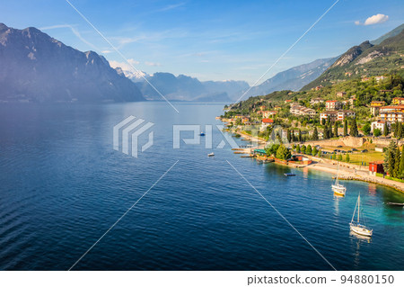 Above idyllic Lake Garda with sailboats in Malcesine at sunrise, Italian alps 94880150