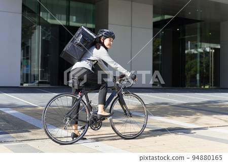 Food delivery woman riding a road bike Female delivery worker 94880165
