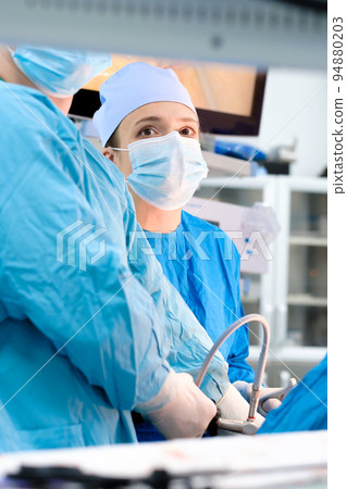 Focused look of female surgeon during surgery. Focused look of female surgeon during surgery. 94880203