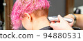 Male hairdresser shaves neck of a young caucasian woman with a short pink hairstyle by electric shaver in a hairdresser salon, close up 94880531