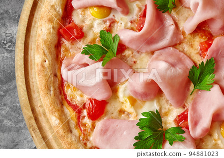 Closeup of pizza with mozzarella, ham slices, quail eggs, tomatoes and greens on wooden serving board Closeup of pizza with mozzarella, ham slices, quail eggs, tomatoes and greens on wooden serving board 94881023