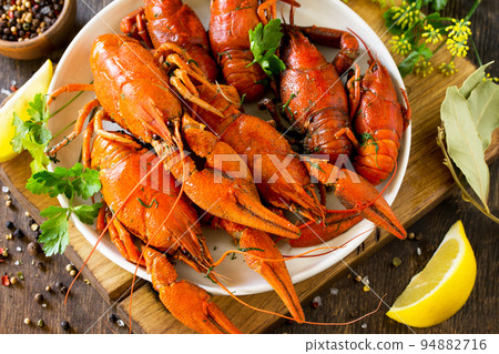Boiled crawfish, lemon and parsley on a wooden table. Appetizer protein, the concept of healthy eating. Boiled crawfish, lemon and parsley on a wooden table. Appetizer protein, the concept of healthy eating. 94882716