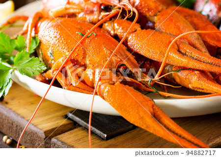 Boiled crawfish, lemon and parsley close-up on a wooden table. Appetizer protein, the concept of healthy eating. Boiled crawfish, lemon and parsley close-up on a wooden table. Appetizer protein, the concept of healthy eating. 94882717