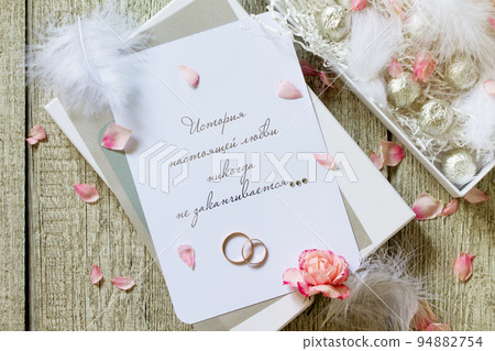 Two Golden Wedding Rings, box of chocolates and a wedding invitation, an inscription that the story of true love never ends. Top view flat lay background. Two Golden Wedding Rings, box of chocolates and a wedding invitation, an inscription that the story of true love never ends. Top view flat lay background. 94882754