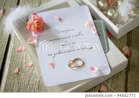 Two Golden Wedding Rings, box of chocolates and a wedding invitation, an inscription that the story of true love never ends. Copy space. 94882772