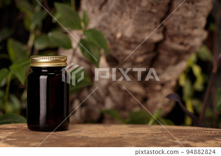 A dark glass container for supplements against the backdrop of nature. MOCK-UP A dark glass container for supplements against the backdrop of nature. MOCK-UP 94882824